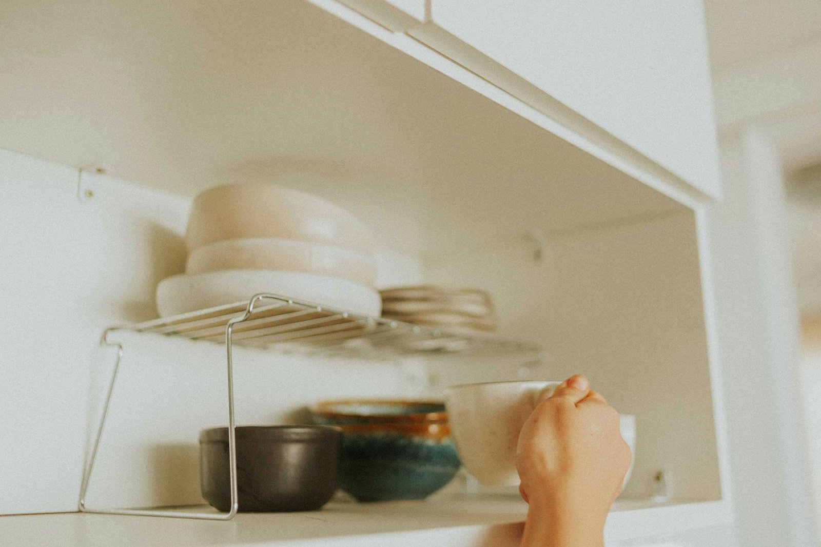 Small cabinet interior showing mugs organized with shelf risers and vertical stackers