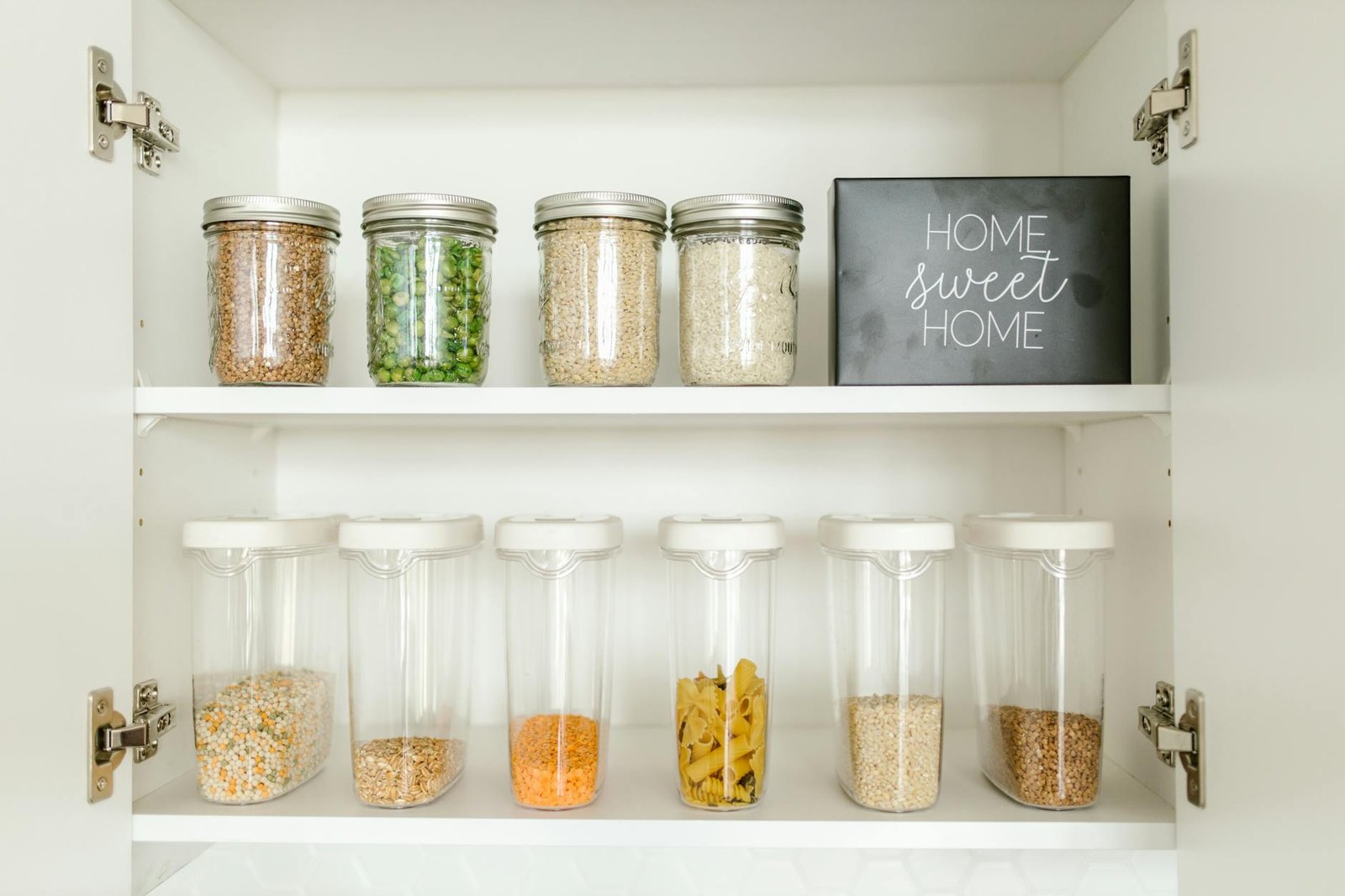 Kitchen cabinet organized into zones for baking supplies, canned goods, and snacks
