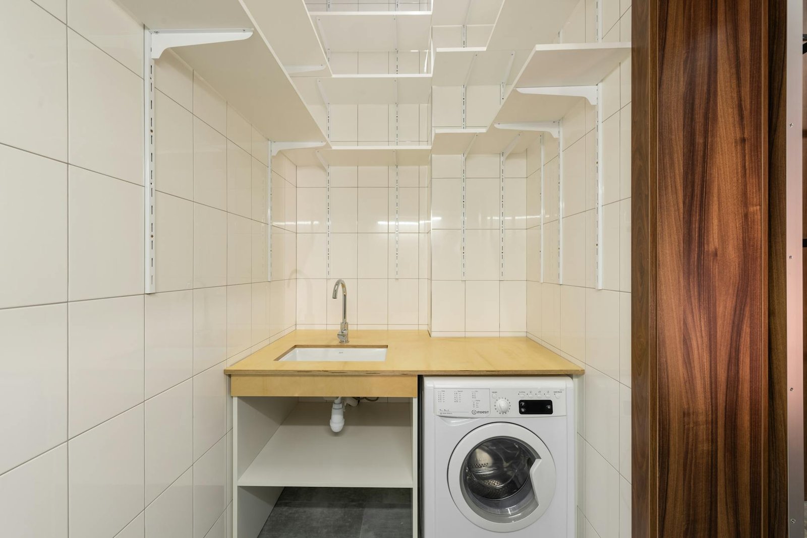 Vertical storage solutions in small laundry room with shelving above machines