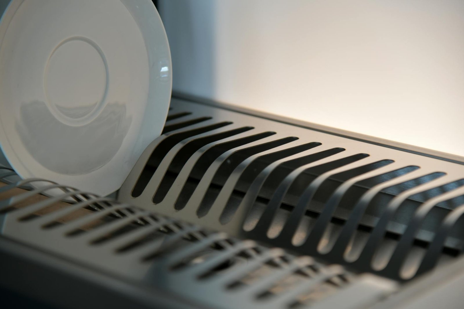 Cabinet door-mounted dish rack with glasses and plates drying inside
